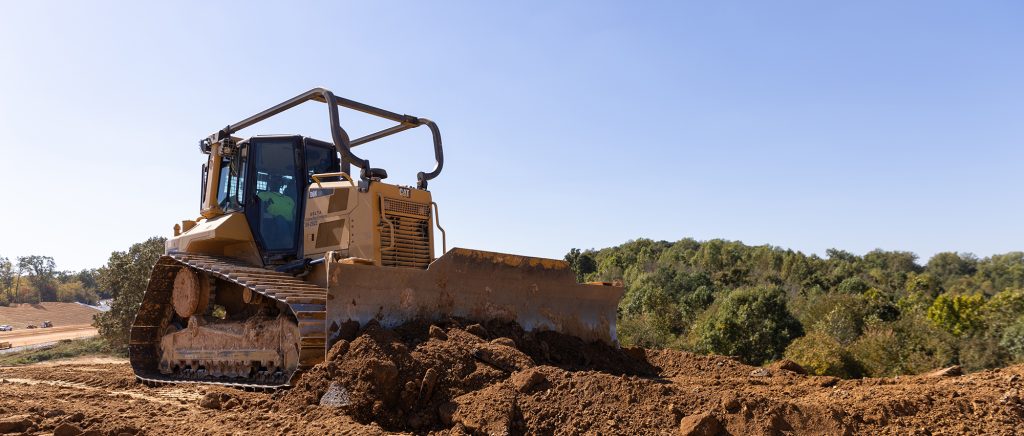 A bulldozer pushing dirt under a blue sky.